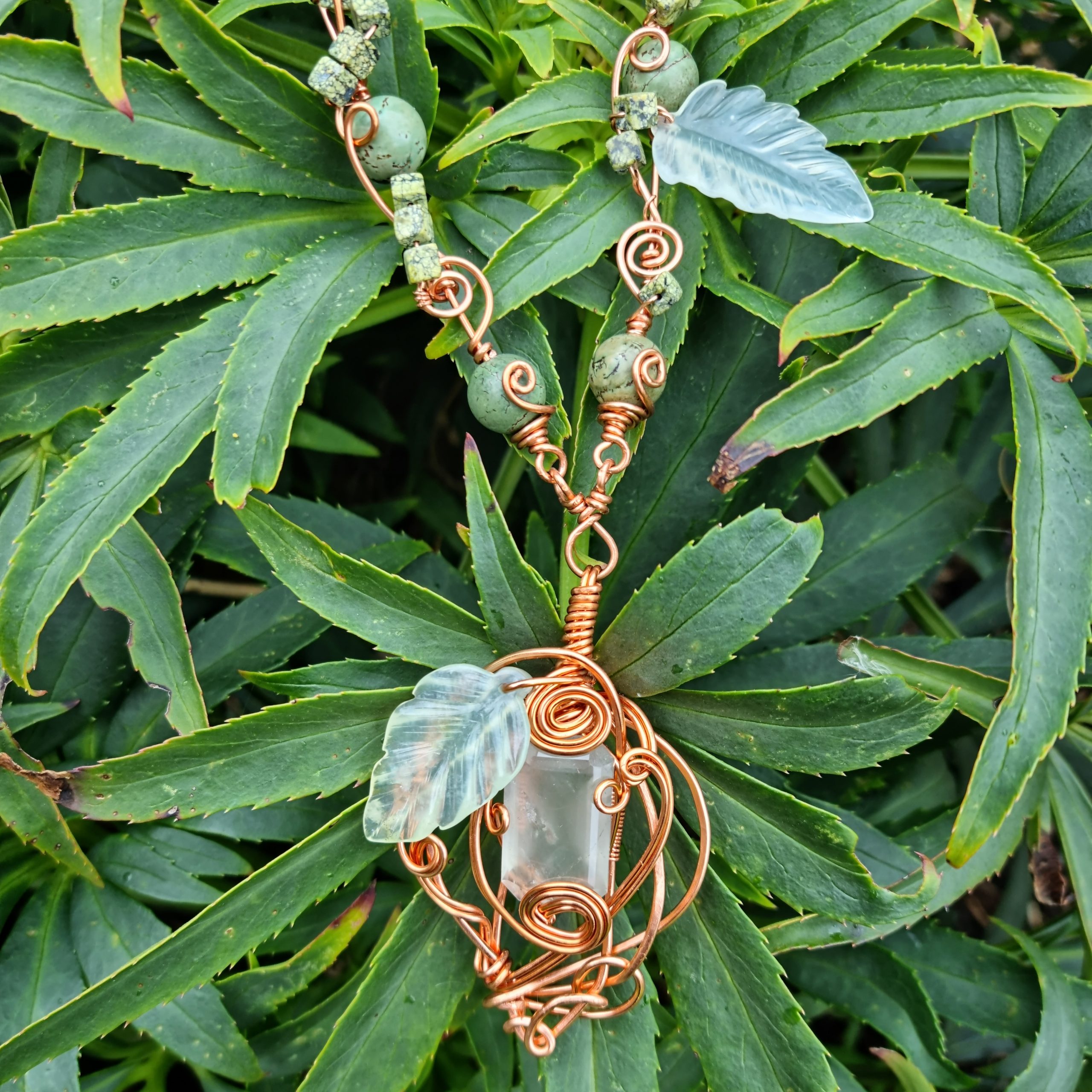 Fluorite, turquoise and Jasper necklace, shot in front of a green plant.