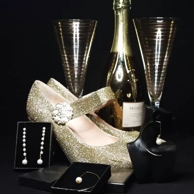 Staged picture of earring with champagne and Gold sparkling shoes