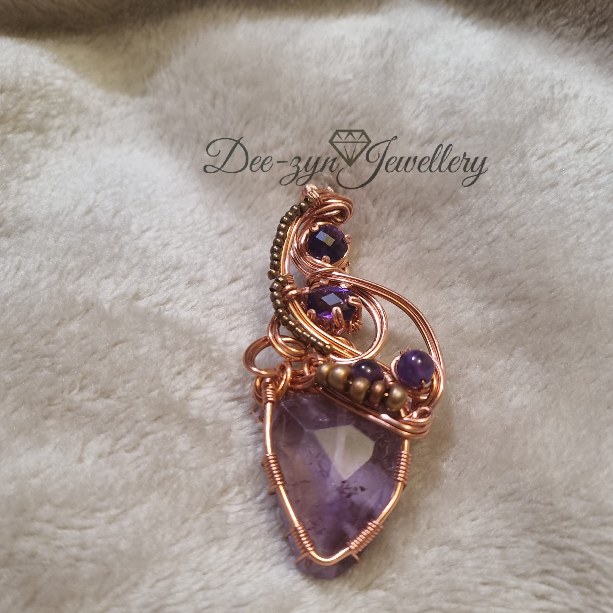 Amethyst Amulet with 5 Amethysts encased in wire on a fur throw.