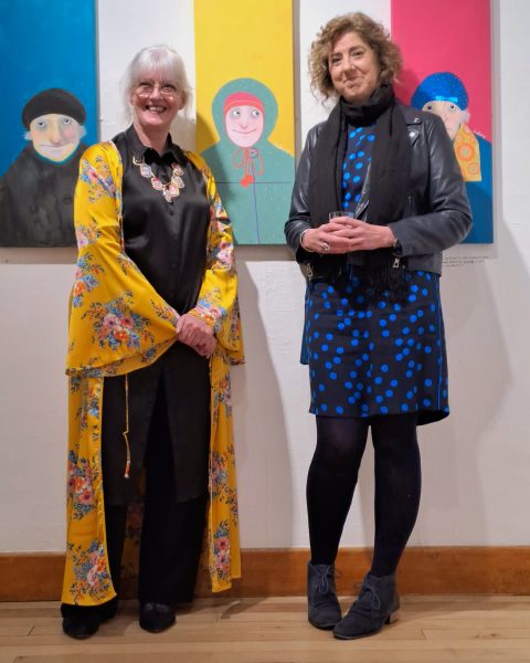 Janet Bates and Ann Bellamy stand in front of Ann's paintings at Peterborough Museum and City Gallery 2023 - photo credit James Tovey 