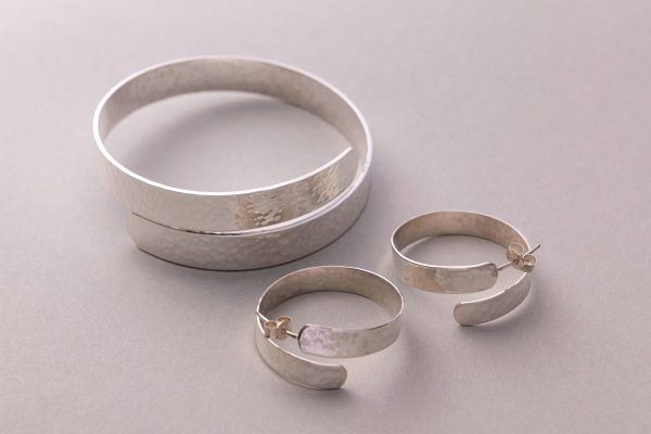 Silver earrings and bracelet on white background.
